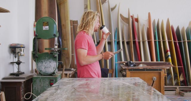 Man Reading Workshop of Surfboards, Holding Coffee - Download Free Stock Images Pikwizard.com