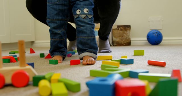 Low section of little black kid with father walking over the building blocks in a comfortable home. Building blocks on the floor 4k
