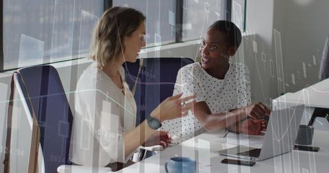Businesswomen Analyzing Financial Data on Laptop in Office
