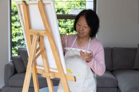 Senior Asian Woman Engaged in Creative Painting at Home Studio
