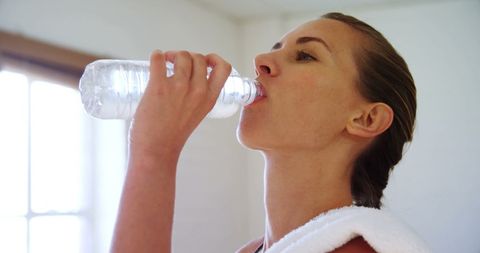 Woman Staying Hydrated in Gym Drinking Water After Workout