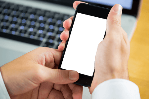 Businessman holding smartphone against laptop transparent screen
