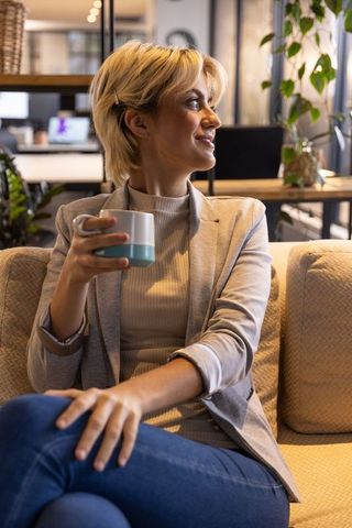 Woman relaxing in modern office lounge with coffee