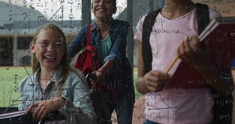 Smiling students pushing wheelchair on campus with math formulas on glass overlay