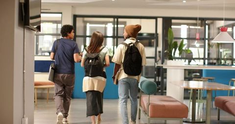 African american students walking in modern campus lounge carrying backpacks