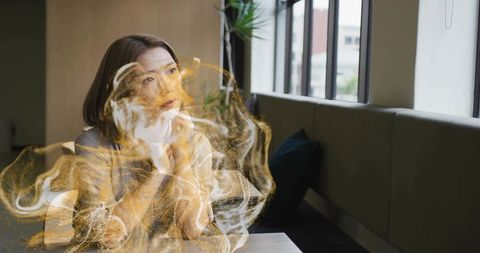 Contemplative Woman at Cafe with Creative Golden Aura Effect