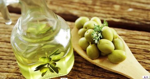 Artisan olive oil with fresh olives on wooden spoon