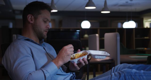 Tired man eating late-night takeout in a dimly lit room - Download Free Stock Images Pikwizard.com