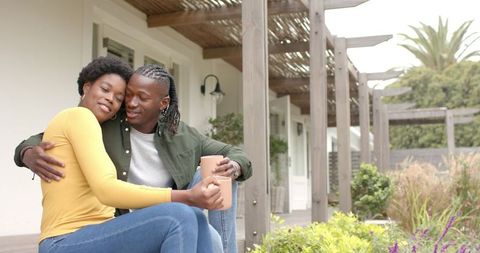 African American Couple Embracing on Porch with Mugs