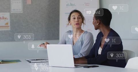 Diverse colleagues collaborating at laptop in boardroom with social media icons