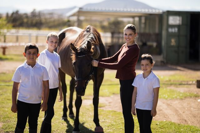 Portrait of happy family standing with a brown horse in the ranch