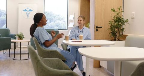 Healthcare staff taking coffee break and conversing in modern clinic lounge during shift