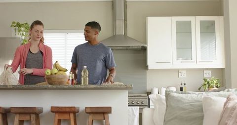 Couple unpacking groceries on granite kitchen island in modern minimalist home