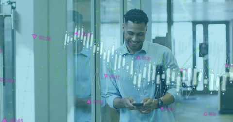 Smiling businessman utilizing mobile phone with digital graphs