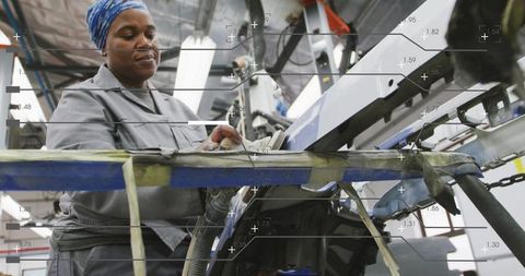 Female technician adjusting assembly-line control panel on industrial production line