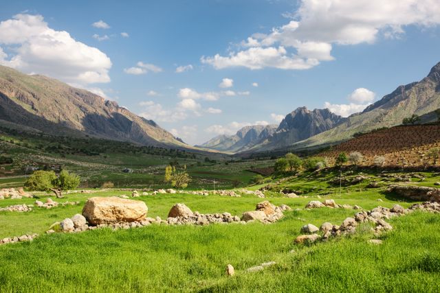 Scenic Mountain Valley with Lush Green Fields and Rocky Terrain - Download Free Stock Photos Pikwizard.com
