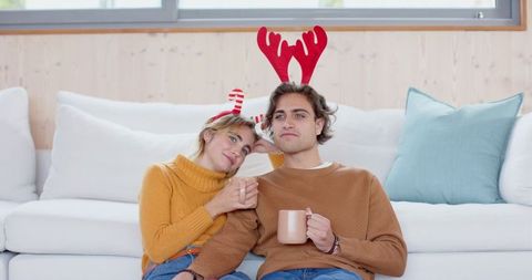 Friends cozying up with hot drinks and festive headbands
