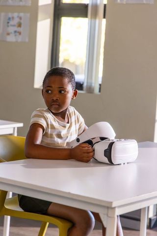 African american schoolboy exploring virtual reality headset in classroom