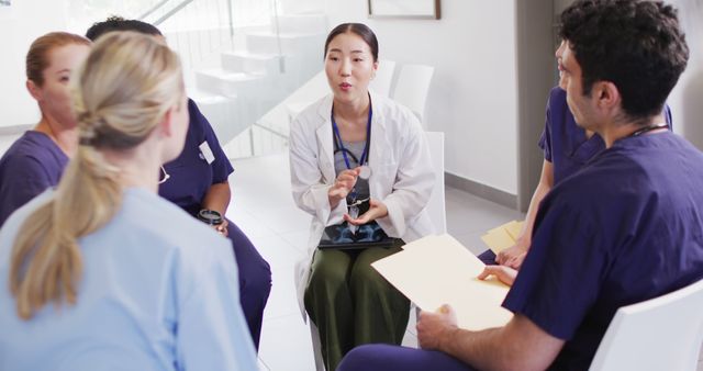 Group of diverse healthcare professionals in a meeting area having a discussion, promoting teamwork and communication in a hospital setting. Ideal for use in content related to healthcare teamwork, medical staff training, collaborative healthcare operations, and internal medical staff meetings.