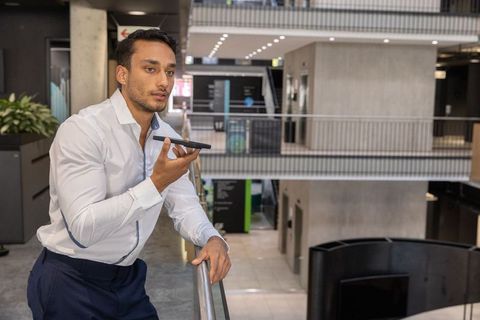 Businessman holding smartphone in modern office atrium