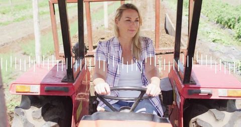 Woman driving red tractor on rural farm field