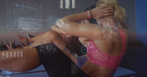 Woman performing crunches wearing wrist tracker during group fitness gym workout session