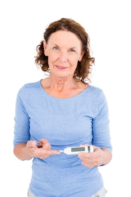 Mature woman checking blood glucose levels with a monitor, smiling at the camera. Useful for health and wellness articles, diabetes awareness campaigns, medical websites, and senior healthcare promotions.