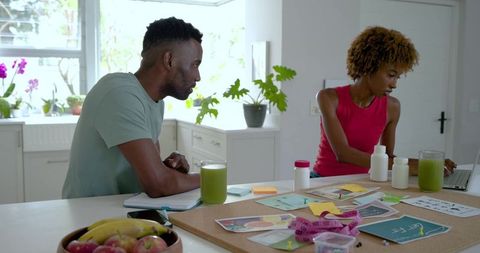 Couple planning wellness and nutrition routine in bright kitchen with smoothies and supplements