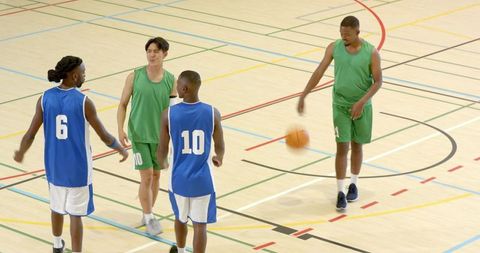Basketball players dribbling at center court starting play showcasing teamwork