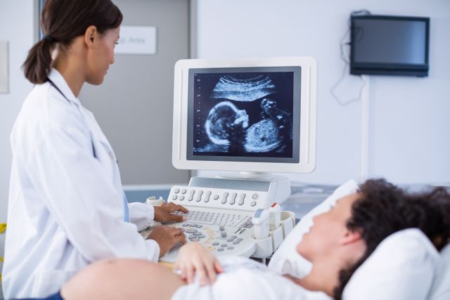Doctor conducting ultrasound scan on pregnant woman in hospital. Useful for topics related to prenatal care, pregnancy, healthcare, medical examinations, and obstetrics. Ideal for medical websites, healthcare brochures, and educational materials on pregnancy and fetal development.