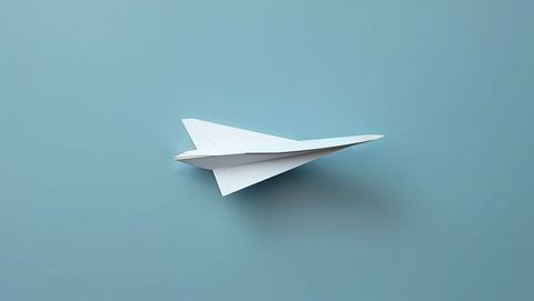 Gliding White Paper Airplane on Pale Blue Backdrop