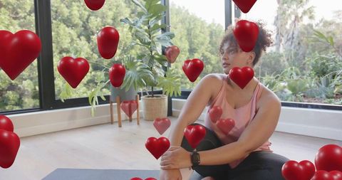 Woman practicing mindful stretch on yoga mat at home surrounded by floating hearts