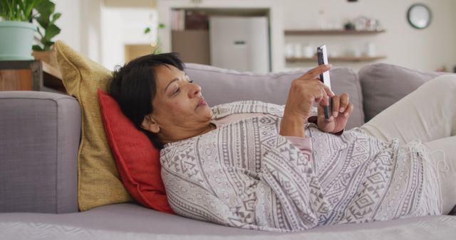 African american senior woman using digital tablet lying on the couch at home. retirement lifestyle living concept