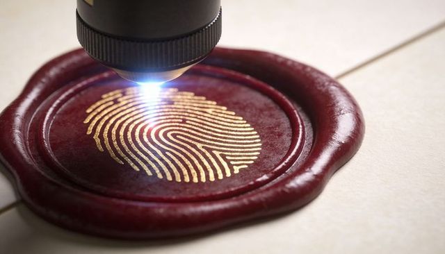 Scanning gold fingerprint embossed on crimson wax seal under blue scanner light for security