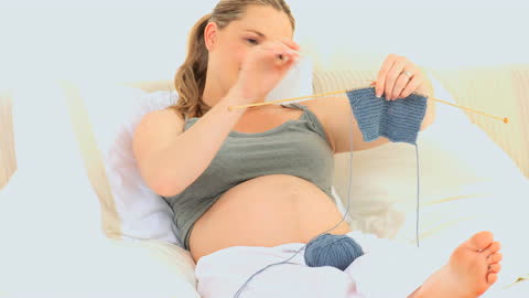 Pregnant Woman Relaxing While Knitting on Bed