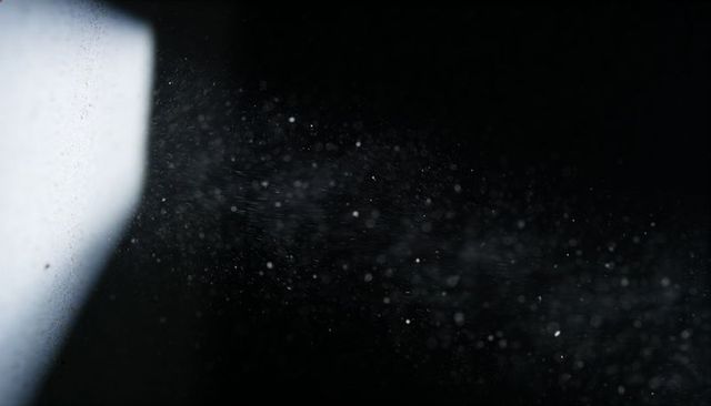 Beam cutting through floating dust and mist on deep black background for dramatic effect