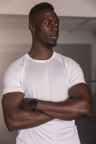 Confident athlete standing in fitness studio with smartwatch