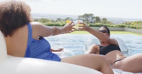 African american women toasting on pool floats enjoying summer relaxation