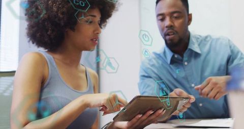 Diverse team collaborating on tablet with futuristic hexagon interface in modern office