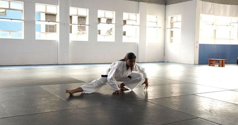 Teenage Martial Artist Stretching in Sunlit Dojo