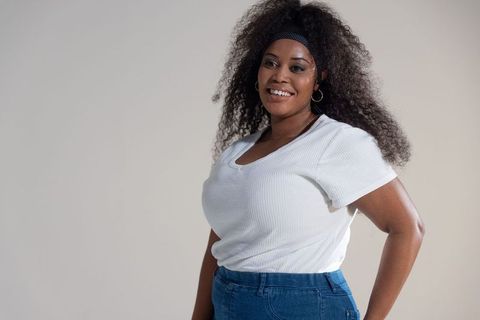 Confident african american woman smiling in white top and jeans, casual fashion portrait
