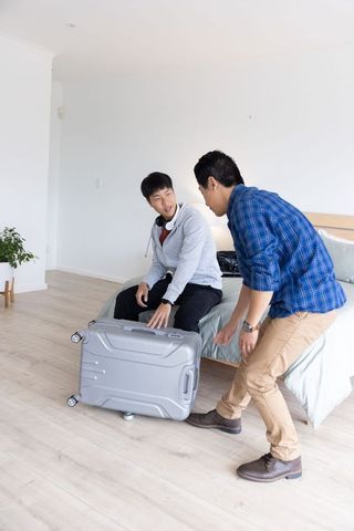 Asian roommates preparing suitcase in bright minimalist bedroom for weekend travel