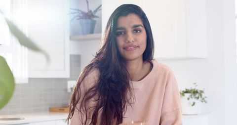 Content Mid Adult Asian Indian Woman Relaxing in Minimalist Kitchen