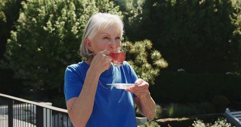 Senior woman enjoying herbal tea on sunny terrace