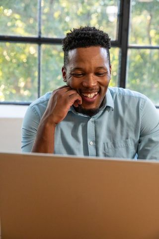 Happy Professional Using Laptop in Bright Workspace