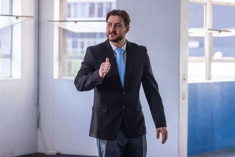 Confident Businessman Giving Thumbs-Up in Corporate Environment