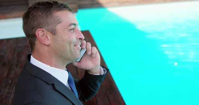 Businessman smiling and talking on smartphone by swimming pool - Download Free Stock Images Pikwizard.com