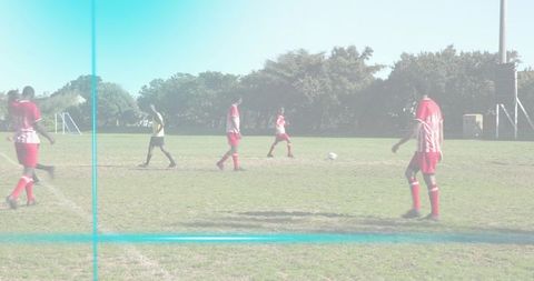 Adult men playing soccer wearing red jerseys on grass field with white ball and referee