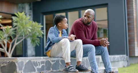 African american father and son having heartfelt conversation while sitting on porch steps