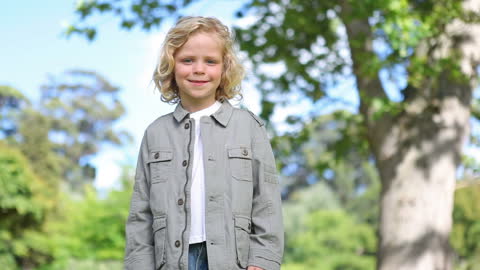 Blond Boy Smiling in Lush Green Park Setting